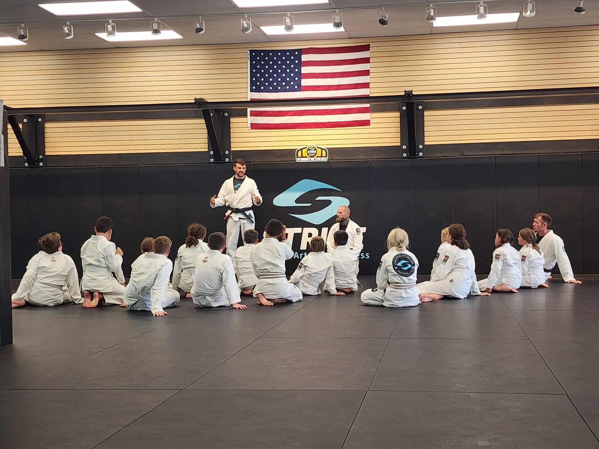Kids Brazilian Jiu Jitsu class sitting with instructors at Stride Martial Arts in Excelsior Springs